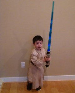 small child with light saber and Ben Kenobi costume