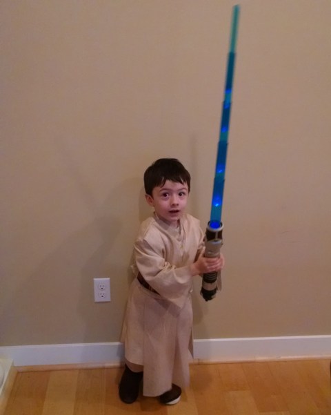 small child with light saber and Ben Kenobi costume
